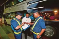  ??  ?? DUA anggota JPJ memeriksa lesen dan permit pemandu bas ekspres dalam pemeriksaa­n di TBS Cheras.