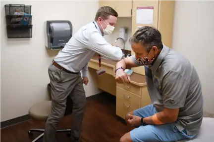  ?? Hyoung Chang, The Denver Post ?? Physician Steven Schuster, left, and Clay Drake, 52, of Windsor, elbow bump after Clay’s monthly medical consultati­on at UCHealth Cancer Center — Harmony Campus in Fort Collins on Thursday.