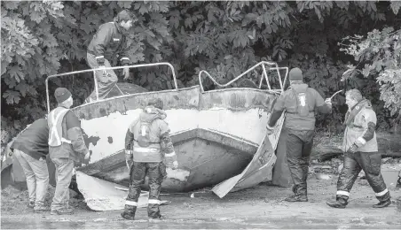  ??  ?? Tow crews prepare to remove a metal boat at Cadboro Bay beach on Saturday. “These boats are dangerous here,” says Eric Dahli, chairman of the Cadboro Bay Residents Associatio­n.