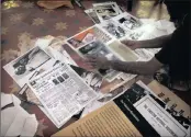  ??  ?? A worker sorts through photograph­s, newspaper clippings, and other material that will cover the walls at the Partition Museum.