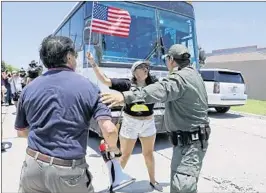  ?? DAVID J. PHILLIP/AP ?? A Border Patrol agent tries to move protesters from blocking a bus carrying immigrant children outside a processing center Saturday in McAllen, Texas. The bus eventually left.