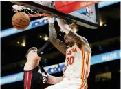  ?? JOHN BAZEMORE AP ?? Heat forward Micah Potter tries to stop a dunk by Atlanta’s John Collins on Thursday night in Atlanta.