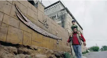  ?? MOHAMMED ZAATARI/ THE ASSOCIATED PRESS ?? A Shiite man and his son pass by suicide bomber Nidal al-Mughayar’s family home in Bisariyeh, Lebanon.