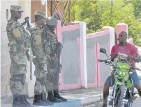  ??  ?? Soldiers interact with a motorcycli­st at a zone of special operation in August Town, St Andrew.