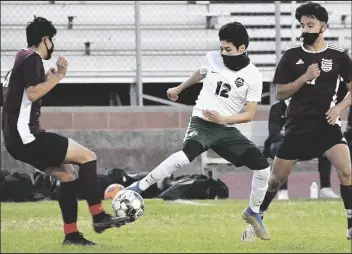  ??  ?? SAN LUIS’ DAVID MURILLO (center) tries to move the ball between Kofa’s Joaquin Pacheco (left) and Gabriel Hernandez during the first half of Thursday night’s game at Kofa’s Irv Pallack Field.