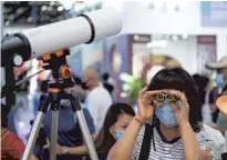  ?? CHEN ZHONGHAO / XINHUA ?? A visitor tries out a pair of binoculars at a Vietnamese exhibition stand during the China Internatio­nal Fair for Trade in Services held in Beijing in 2021.