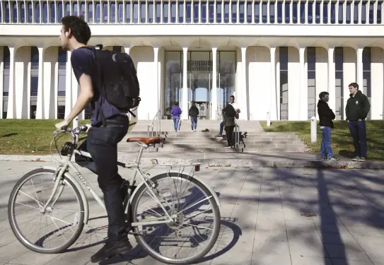  ?? (Reuters) ?? A MAN cycles past Princeton University’s Woodrow Wilson School of Internatio­nal Relations.