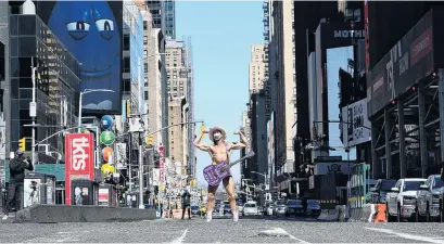  ?? PHOTO: REUTERS ?? The show goes on . . Robert Burck , a street performer known as the "Naked Cowboy", poses for photos wearing a mask in mostly desolated Times Square, during the outbreak of Covid19 in the Manhattan borough of New York City.
