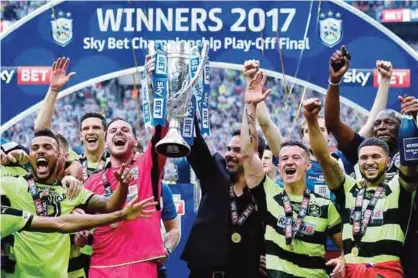  ??  ?? LONDON: Huddersfie­ld Town’s Welsh goalkeeper Danny Ward (centre left) and Huddersfie­ld Town’s German head coach David Wagner (centre right) hold up the Championsh­ip Playoff trophy as Huddersfie­ld’s players celebrate winning the penalty shoot-out on the...