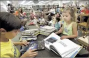  ??  ?? Brayden Douglas, 7, and his sister, Emily, 3, check out a selection of books during a special children’s program. The Hernando-based First Regional System of libraries serves DeSoto and four other counties.