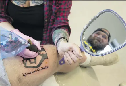  ?? SHAUGHN BUTTS ?? Tattoo artist Jesse Jones inks customer and Edmonton Oilers super-fan Darcy Niedzielsk­i with an Oilers Nation logo at Shambhala Tattoos in Old Strathcona on Wednesday.