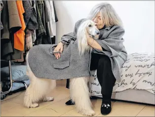  ??  ?? In this image taken on Thursday, Jan. 11, 2018, designer Giovanna Temellini kisses her dog Ulisse, an Afghan greyhound, wearing a winter coat created by Ms. Temellini, at the Temellini manufactur­e headquarte­rs, in Milan, Italy.