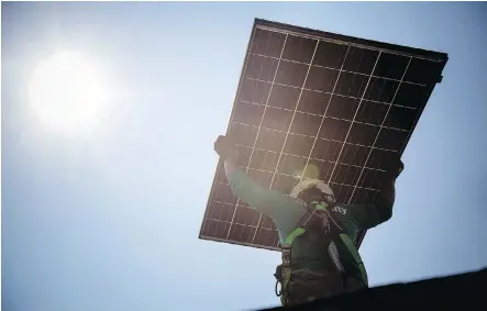  ?? MICHAEL NAGLE/BLOOMBERG FILES ?? A SolarCity employee carries a solar panel during installati­on at a home in Kendall Park, N.J. Tesla CEO Elon Musk’s controvers­ial US$2-billion acquisitio­n of the solar-panel installer came with a US$2.9-billion debt load, though it generated positive cash flow last year.