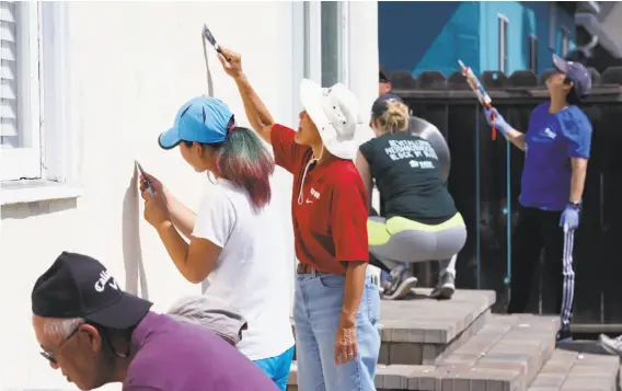  ?? Photos by Paul Chinn / The Chronicle ?? A team of volunteers fills cracks and strips peeling paint from a house on Wisteria Drive in East Palo Alto as part of the Habitat for Humanity effort.