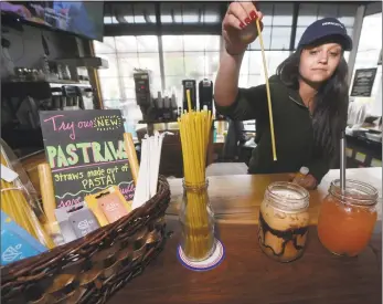  ?? Erik Trautmann / Hearst Connecticu­t Media ?? Harbor Harvest barista Brittany Tarantino serves up a Rise Nitro cold-brew coffee drink with its new pastraws, a pasta straw, and a lemon ginger iced tea with the reusable Ultimate Straw on Wednesday in Norwalk.