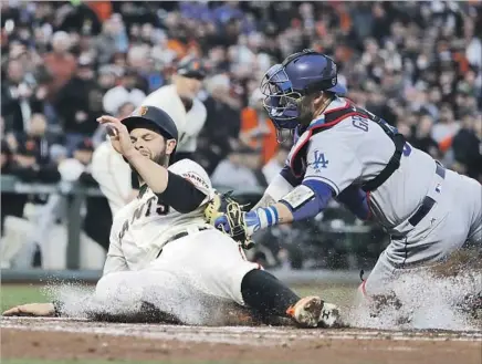  ?? Marcio Jose Sanchez Associated Press ?? DODGERS CATCHER Yasmani Grandal tags out San Francisco’s Brandon Belt amidst a cloud of dust at home plate in the first inning. Belt was trying to score on a two-out single by Buster Posey, but Yasiel Puig threw him out from right field.