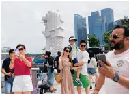  ?? Photo: EPA ?? Tourists pose for photos last week at Merlion Park in the heart of Singapore, with Marina Bay Sands in the background.