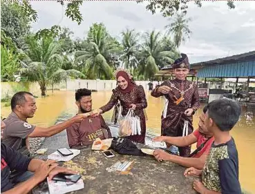  ?? BERNAMA PIC ?? Nur Izzatul Asma Mustafa and her fiancé Mohamed Khairie Mohamed Kamal handing out ‘nasi kenduri’ to the public after their wedding in Alor Star, Kedah yesterday.
