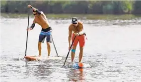  ?? KIM HAIRSTON/BALTIMORE SUN ?? Joe Ward, left, and Chris Norman, both of Annapolis, push toward the finish line during Saturday’s paddle board races on Dundalk’s Bear Creek.