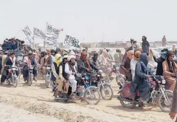  ?? TARIQ ACHKZAI/AP ?? Taliban supporters carry their signature white flags July 14 after the Taliban said they seized the Afghan border town of Spin Boldak across from Chaman, Pakistan. The Taliban want President Ashraf Ghani removed from office.