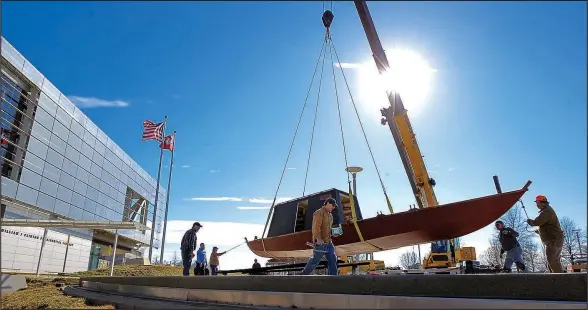  ?? File Photo/BENJAMIN KRAIN ?? Ed Williams, right, with Early Arkansaw Re-enactors Associatio­n, holds steady a replica his group built of the Aux Arc keel boat, as workers with Campbell Sheet Metal install it in front of the Clinton Presidenti­al Center. The original boat was used by...