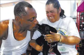  ??  ?? Carl Graves and fiancee Monica Salas play with their dog Chico on Saturday at their encampment behind EZ Pawn. Graves said, “I don’t want to die here on the streets and be remembered as a nobody.”