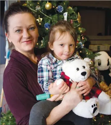  ??  ?? Raelene Tamblyn’s 2 1/2 year old granddaugh­ter Avianna cuddles with a new teddy bears at the Westside food depot Monday morning. Tamblyn was picking up a Christmas hamper on behalf of her daughter, who had started a new job that day.