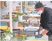  ?? FOTO: OLIVER BERG/DPA ?? Ein Kellner räumt den Tisch in einem Restaurant in Aachen ab. Die Gastronome­n leiden nach wie vor stark unter der Pandemie.