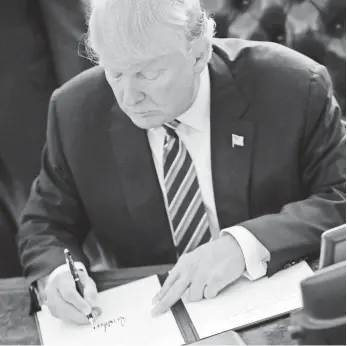  ?? PABLO MARTINEZ MONSIVAIS, AP ?? President Trump signs one of three executive orders on crime Thursday in the Oval Office.