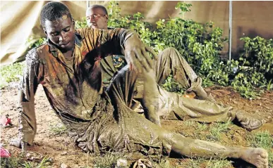  ?? /PHOTOS: REUTERS ?? Above left, a rescued miner is carried from a pit, and above, a mine rescuer climbs out of a shaft as efforts to retrieve more trapped miners proceed in Kadoma, Zimbabwe. Rescue workers retrieved 24 bodies and eight survivors from the flooded gold mines on Saturday, but government officials fear that dozens more may still be trapped inside the mines.