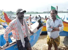  ??  ?? Solomon (right) and Francis, fishermen from Kollam who took part in recent rescue operations in the floods that devastated the south Indian state of Kerala, stand near a boat that was damaged during the rescue. — AFP photo