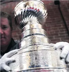  ?? CHARLES KRUPA/THE ASSOCIATED PRESS ?? Mike Bolt, a keeper of the Stanley Cup, holds onto the trophy’s top layer, which will be removed from the 126-year-old cup to make room for the next generation of champions.