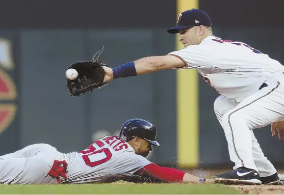  ?? AP PHOTO ?? STAY CLOSE: Mookie Betts beats the tag by Joe Mauer on a pickoff attempt during the fifth inning of the Red Sox’ 6-2 loss to the Minnesota Twins last night in Minneapoli­s. The Sox fell a game behind the Yankees in the AL East.