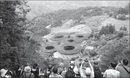  ?? HU GUANGHE / XINHUA ?? Tourists photograph tulou in Tianluoken­g village, Zhangzhou city, Fujian.