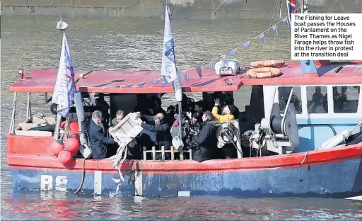  ??  ?? The Fishing for Leave boat passes the Houses of Parliament on the River Thames as Nigel Farage helps throw fish into the river in protest at the transition deal