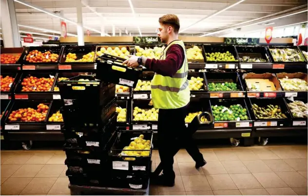  ?? Reuters ?? ±
An employee arranges produce inside a Sainsbury’s supermarke­t in Richmond, west London, Britain.