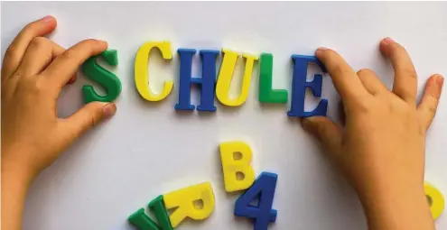 ?? FOTO: ARNO BURGI / DPA ?? Ein Kind schreibt mit Magnetbuch­staben das Wort „Schule“an eine Magnettafe­l,. Magnete halten sich wie von selbst fest.