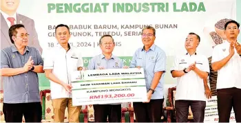  ?? — Photo by Mohd Faisal ?? Vincent (second left) and Martin (third left) handing over a mock cheque of the STLB assistance to a representa­tive from Kampung Mongkos.