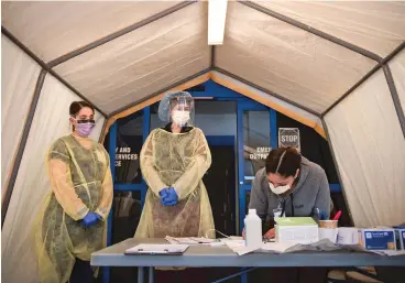  ?? MORGAN TIMMS/TAOS NEWS ?? ABOVE: From left, nurse technician Antonia Barela, emergency room nurse Andrea Magee and registered nurse Benito Lovato prepare March 23 for an influx of patients and gusts inside the screening tents at Holy Cross Hospital in Taos.