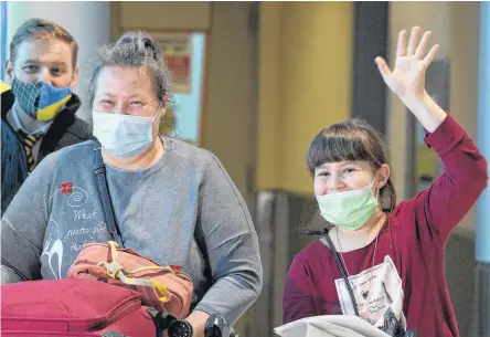  ?? KEITH GOSSE • SALTWIRE NETWORK ?? Zoriana Shapoval, 9, waves excitedly as she spots her sister, Sofiia, in a crowd of people greeting Ukrainian refugees at St. John’s Internatio­nal Airport Monday night. At left is her mother, Natalia. Looking on is Premier Andrew Furey.