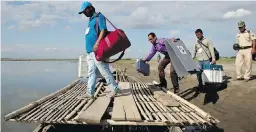  ??  ?? Election officials and paramilita­ry soldiers with voting materials board a raft to cross the Brahmaputr­a River to reach remote parts of the northeaste­rn state of Assam, India.