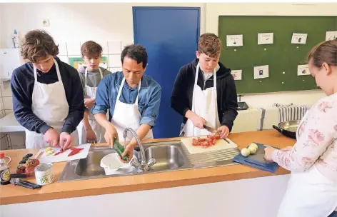  ?? RP-FOTO: ACHIM BLAZY ?? Gastlehrer Zulkanain Hasan Abdullah wäscht das Gemüse, während die Schüler schon mal schnibbeln..