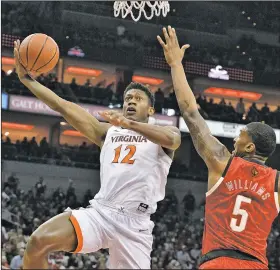  ?? AP/TIMOTHY D. EASLEY ?? Virginia guard De’Andre Hunter attempts a shot over the reach of Louisville center Malik Williams during the first half Saturday in Louisville, Ky. Hunter scored a career-high 26 points, rallying the Cavaliers to a 64-52 victory.