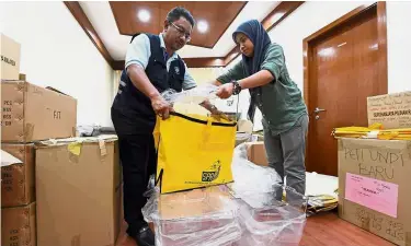  ??  ?? On the job: Election Commission personnel sorting out newly arrived ballot boxes at the Operations Centre in Putrajaya yesterday. — Bernama