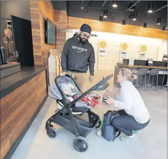  ?? [TOM DODGE/DISPATCH] ?? H.P. Bath, manager of the Amazon Pickup store, assists Michelle Doyle with returning an item. Doyle’s infant son Hank is along for the ride.