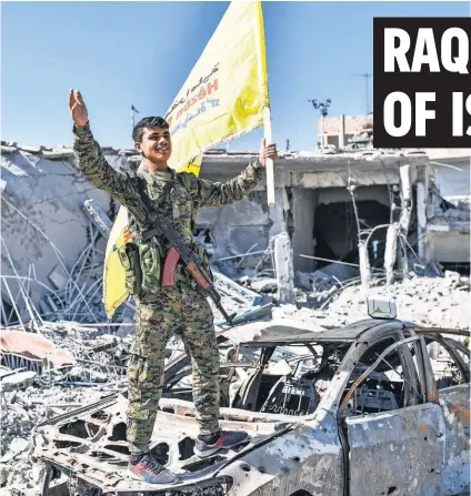  ?? Amember of the Syrian Democratic Forces ( SDF), a faction backed by U. S. special operations forces, hoists the SDF flag in Al- Naim square in Raqqa on Tuesday. Fighters said they had taken control of Raqqa from the Islamic State group, defeating the last ??