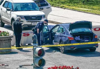  ?? J. Scott Applewhite / Associated Press ?? U.S. Capitol Police officers investigat­e the car that crashed into a barrier on Capitol Hill on Friday. Police identified the slain officer as William “Billy” Evans, an 18-year veteran who was a member of the department’s first responders unit.