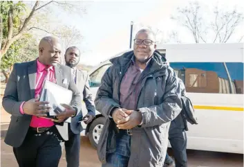  ?? — AFP ?? Tendai Biti of Zimbabwe’s main opposition Movement for Democratic Change arrives in handcuffs at the Harare Magistrate­s court on Thursday.