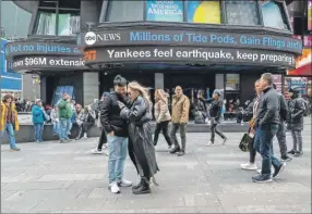  ?? ?? Personas recorren Times Square de Nueva York mientras las pantallas muestran noticias sobre el sismo de ayer. En una oficina en un 26o. piso del centro de Manhattan (a la izquierda), Shawn Clark sintió el sismo e inicialmen­te temió que hubiera ocurrido una explosión o un accidente de construcci­ón