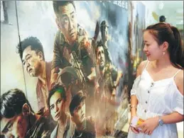  ?? WANG BIAO / FOR CHINA DAILY ?? A young moviegoer looks at a poster for the Chinese film Wolf Warriors II at a cinema in Fuyang, East China’s Anhui province.